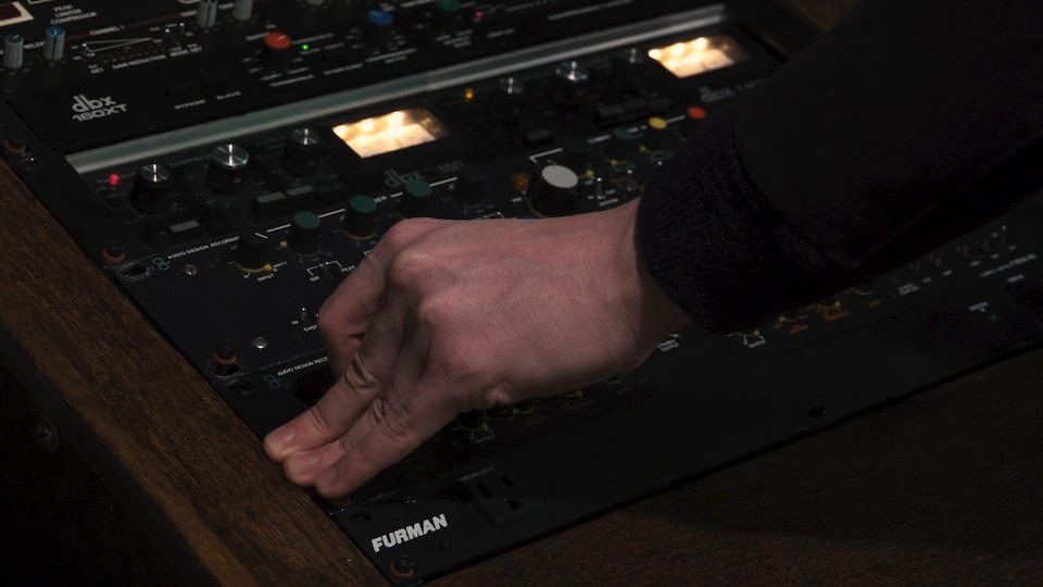 Une main sur une console analogique.